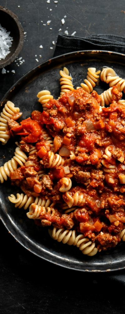 Pasta with sauce bolognese served on plate on dark background.